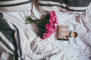 flowers, book, and coffee left on a bed as a sweet favor