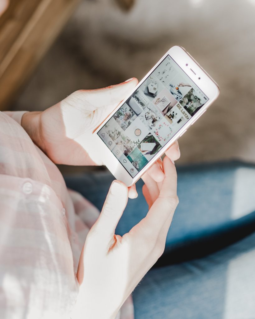 woman holding phone scrolling through social media