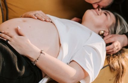 A man leaning in to kiss a pregnant woman