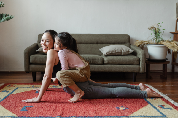 Woman doing yoga with her daughter on her back