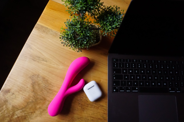 pink sex toy near airpods and laptop