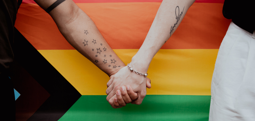 holding hands in front of pride flag