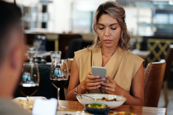 a woman using her phone during a meal in a restaurant