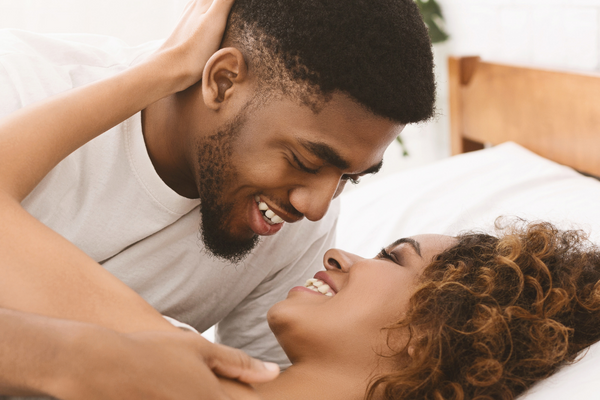 a man and a woman smile at each other in bed
