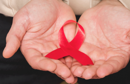 Red ribbon in hands for HIV awareness