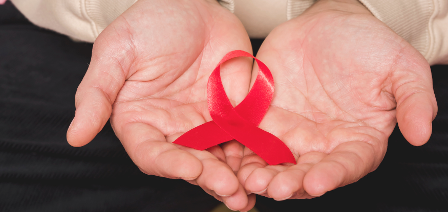 Red ribbon in hands for HIV awareness